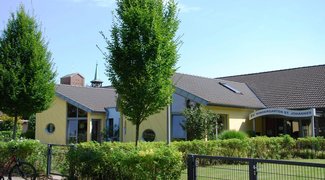 Hellgelbes Kitagebäude im Sonnenschein